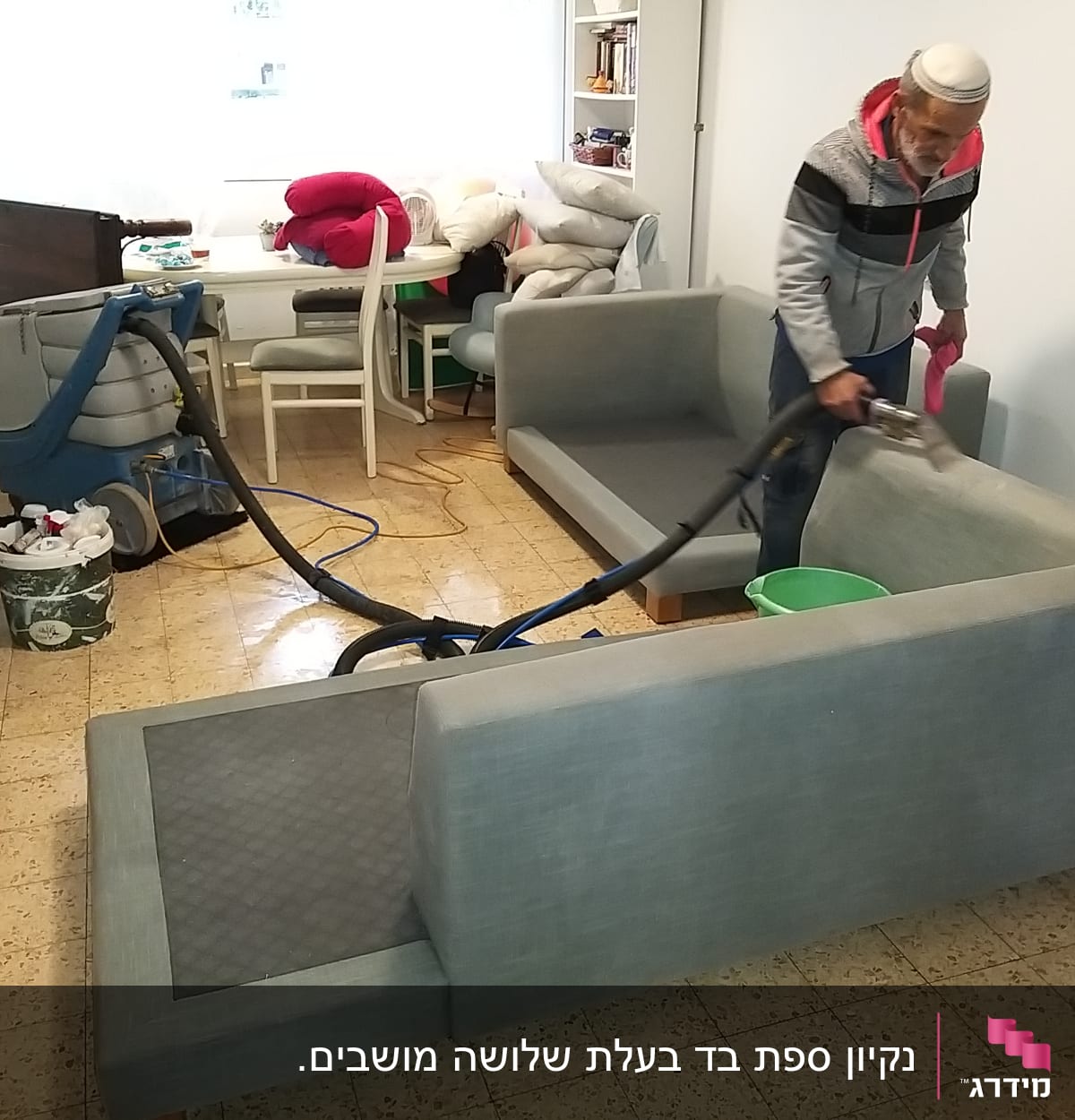 אדם מנקה ספה עם מכונת ניקוי ושואב אבק